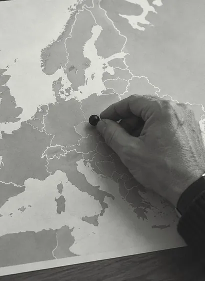 Eine Hand setzt einen Marker auf eine Europakarte ohne Beschriftung